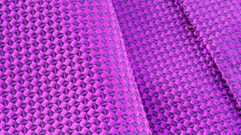 Close-up of rich purple woven fabric with a tactile basket-weave texture, folded in soft layers